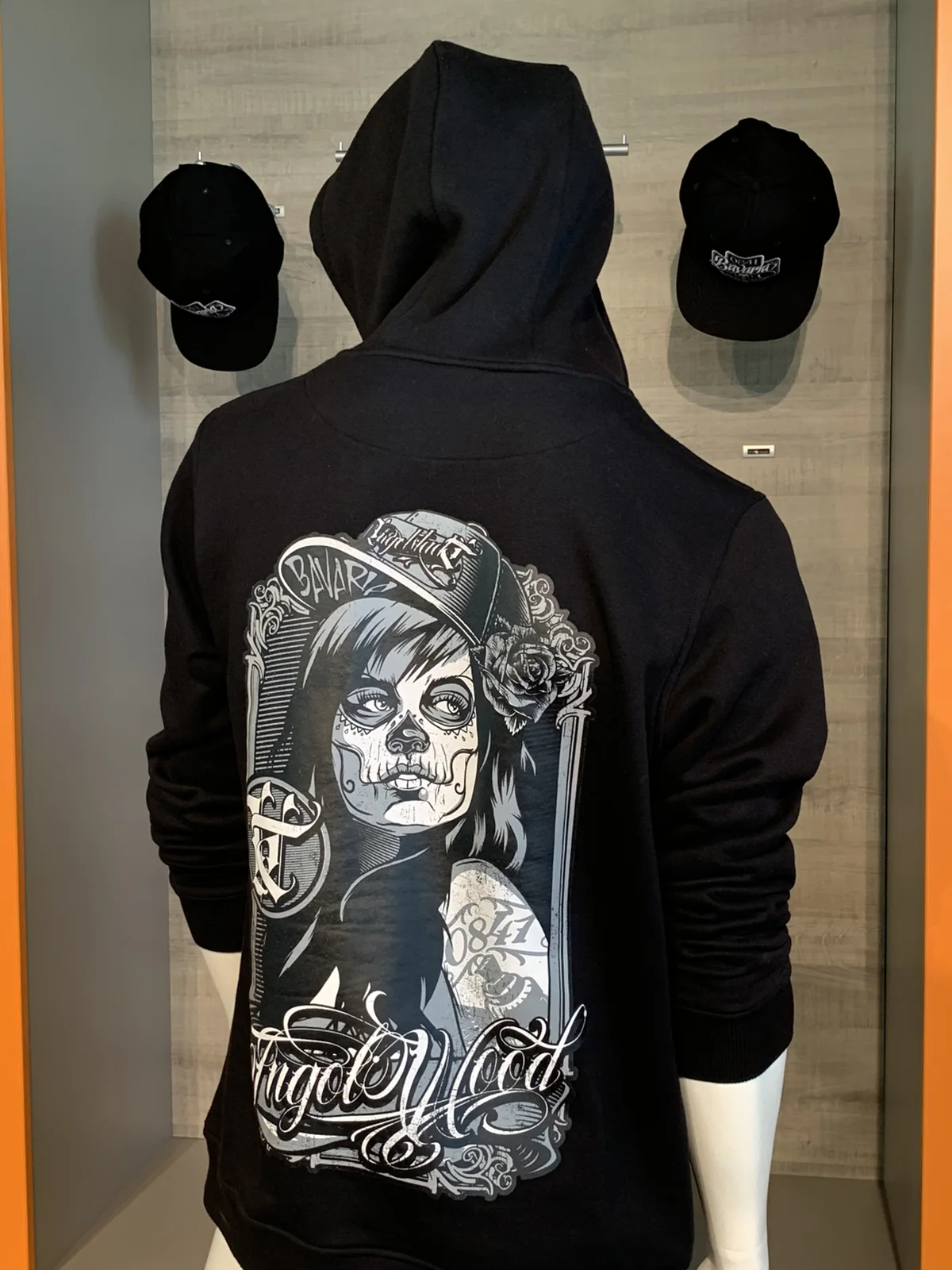 Schwarzer Hoodie von hinten mit großem Motiv: Frau mit Cap, Rosen und Ingolwood-Schriftzug