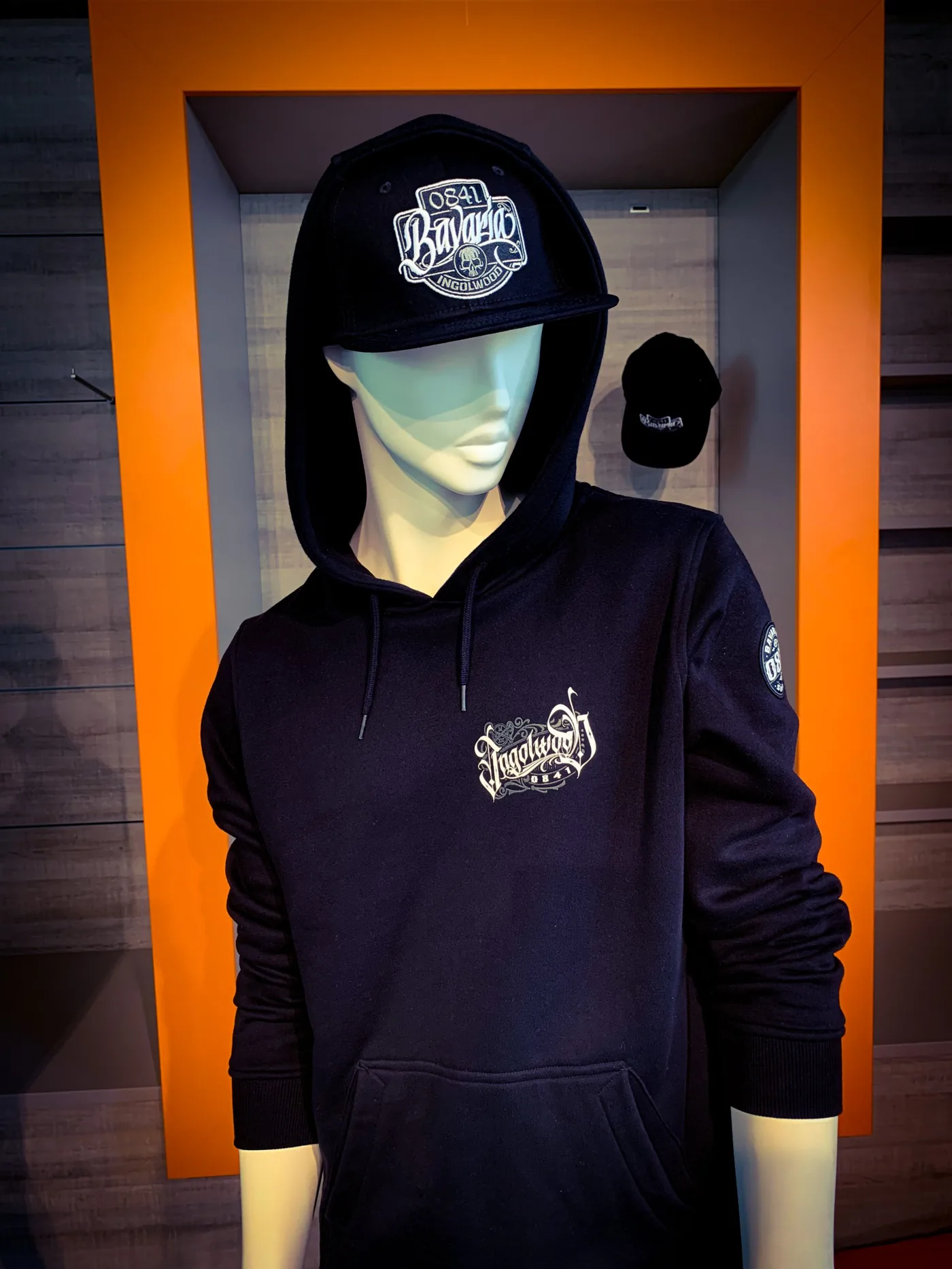 Schwarzer Hoodie mit Ingolwood-Logo auf der Brust und Snapback-Cap mit Bavaria-Patch