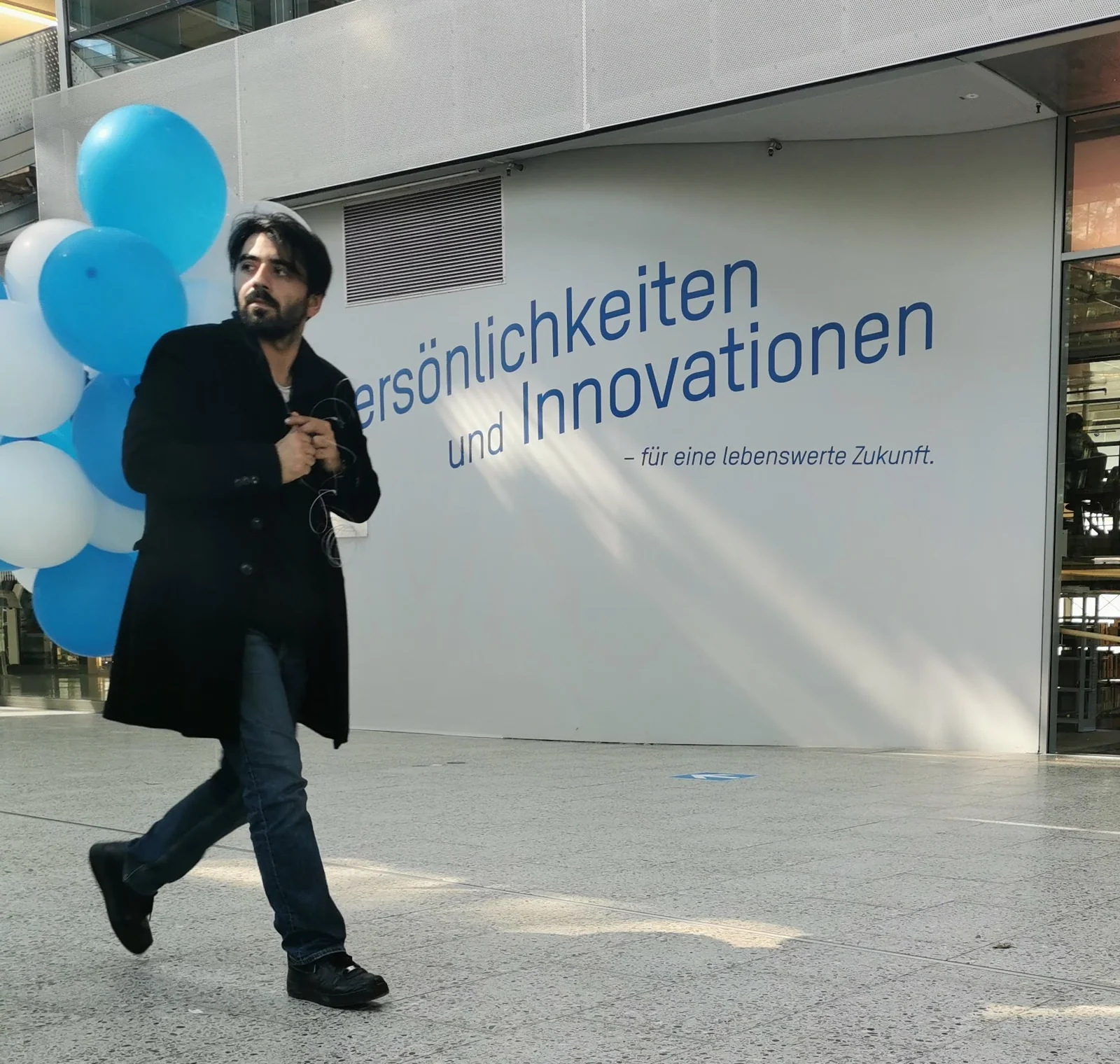 Merab Paresi mit blauen und weißen Luftballons in der Halle der Technischen Hochschule Ingolstadt, im Hintergrund der Schriftzug Persönlichkeiten und Innovationen